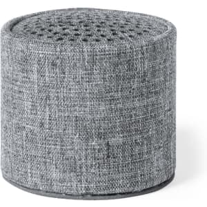 A round grey speaker covered in textured fabric, featuring a perforated top design and a solid base.