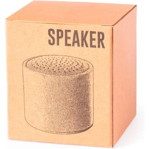 A brown cardboard box containing a cylindrical speaker design with a textured surface. The box has a logo.
