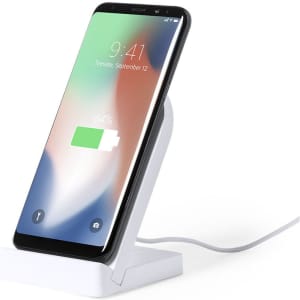 A white wireless charger with a smartphone placed upright, displaying a battery charging icon on the screen.