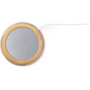 A round cup warmer with a wood base and metallic heating surface, featuring a white power cord.