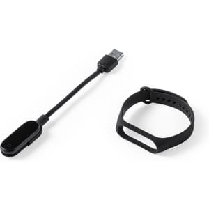 A black smart bracelet beside its USB charging cable. The bracelet has an adjustable strap and a minimalistic design.