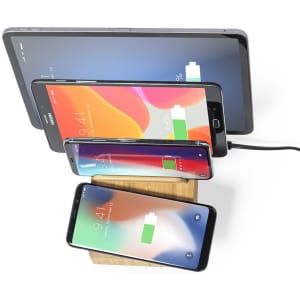 A wireless charger in a wooden stand, charging multiple devices including smartphones and a tablet in various colours.