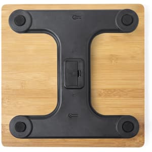 A black weighing scale with a wooden base, featuring a sturdy, minimalist design and rubber feet for stability.