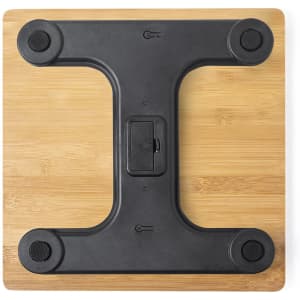 A black weighing scale with a wooden base, featuring rounded corners and rubber grips.
