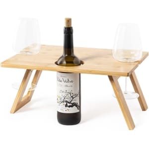 A bamboo table with a bottle of wine and two glasses, featuring a wooden design and detachable legs.
