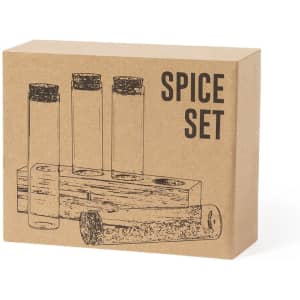 A spice set in a cardboard box featuring four glass containers with cork lids. The design is simple and rustic.