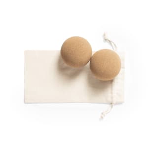 Two tan balls made from a textured material, resting on a cream-coloured pouch. The pouch has a drawstring closure.