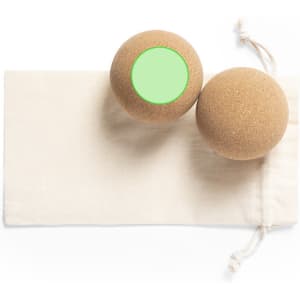 A set of two brown balls with a green circular area, resting on a light beige cloth pouch.