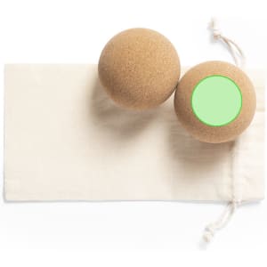 A set of two tan balls with a green circle, resting on a beige cloth pouch.