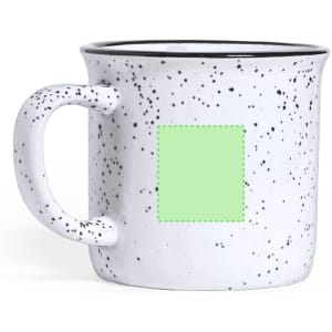 A speckled white coffee mug with a green blank area for customisation and a black rim.