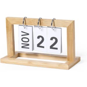A tabletop calendar featuring a wooden frame with three flip cards displaying the month and day in bold black text.