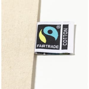 A natural-coloured tote bag with a Fairtrade label visible on the side. The bag features a simple design.