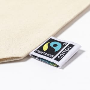 A cream toiletry bag featuring a Fairtrade label. The bag has a simple design and is made from cotton.