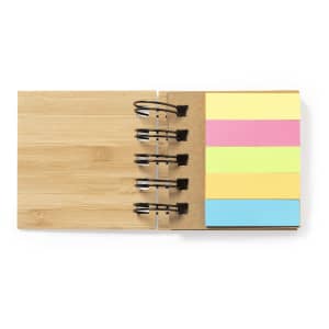 A bamboo sticky notepad featuring pastel-coloured notes in pink, yellow, and blue, secured with black binder clips.