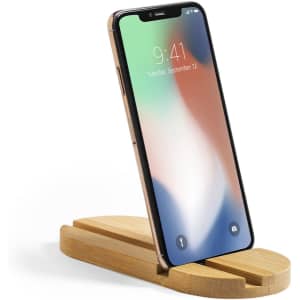 A wooden phone stand in a light colour holding a smartphone upright, displaying a colourful screen.