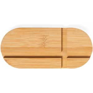 A bamboo phone stand in a simple oval shape with grooves for device placement. It features a natural wood finish.
