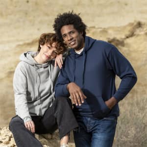 A grey and a navy hooded sweatshirt modelled by a man and a woman, both styled casually outdoors.