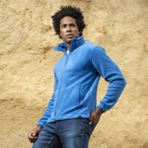 A polar fleece jacket in bright blue, featuring a zip front and side pockets, modelled by a person against a textured background.