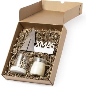 A gift box featuring a candle, a decorative piece shaped like a tree, and shredded paper filling, all in a natural cardboard box.