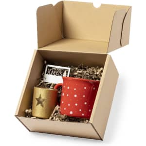 A red mug with white stars and a gold cup with a star, packaged in a brown gift box with shredded paper.