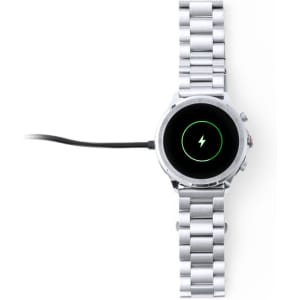 A silver smartwatch with a metal band and a charging cable attached. The watch has a circular display.