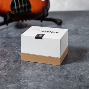 A white and brown box labelled as a limited edition product, set on a grey surface with a guitar in the background.