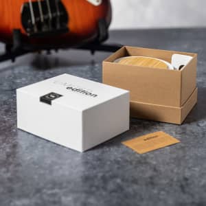 A wooden multifunction lamp in a brown box, with a white outer box and a small card on a textured surface.