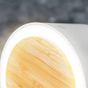 A multifunction lamp with a white base and a bamboo top, featuring a soft glowing light.