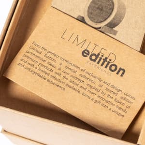 A cardboard box containing a promotional card, featuring a logo and text about a limited edition product experience.