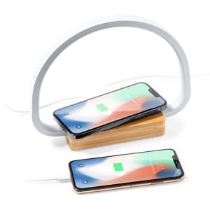 A wireless charger lamp with a sleek white arch design and a wooden base, featuring two smartphones charging.