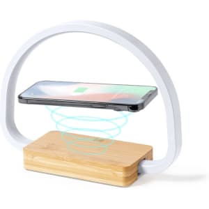 A wireless charger lamp featuring a curved white design and a bamboo base, with a smartphone positioned above.