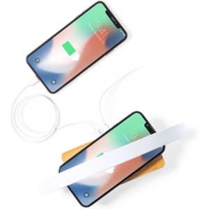 A wireless charger in a wooden base with two smartphones charging, featuring a sleek white design.