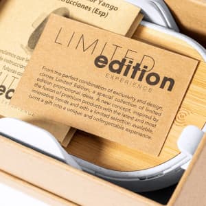 A wireless charger holder in white, featuring a logo, nestled in a cardboard package with a limited edition card.