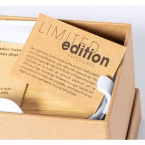 A cardboard box with a limited edition card and a wireless charger holder inside, featuring a natural wood finish.