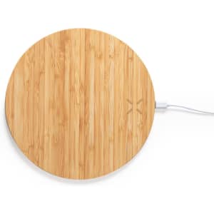 A round bamboo wireless charger with a minimalist design and a white charging cable attached.
