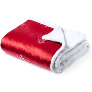 A red and white blanket with a soft texture, featuring snowflake patterns on one side. It has a fluffy white lining.