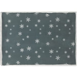 A soft grey blanket featuring a pattern of white snowflakes, edged in a cream trim. It has a branding logo.