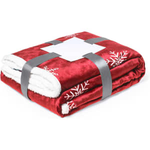 A folded red blanket with a fluffy white interior, featuring snowflake designs and secured with a grey strap.