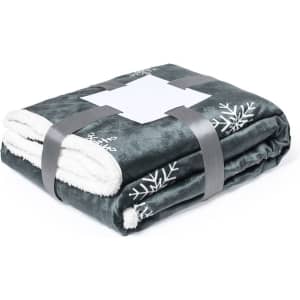A folded grey blanket with a white fleece lining, featuring snowflake designs and secured with a grey strap.