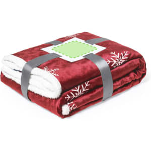 A red and white plaid blanket with snowflake designs, neatly folded and secured with a grey strap.