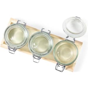 A wooden tray with three glass jars, featuring metal clasps and clear lids. Jars are empty and transparent.