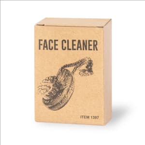 A cardboard box containing a face cleansing brush, featuring a graphic illustration. The box is brown with a simple design.