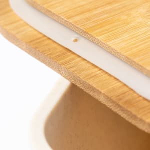 A close-up of a bamboo lid and silicone seal in a natural-toned container, featuring sleek design and texture.