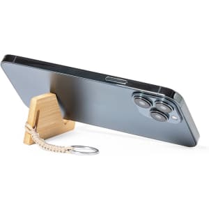 A sleek smartphone propped on a wooden stand, featuring a beige keyring attached. The phone has a shiny black back.