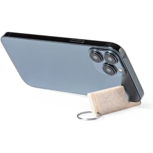 A keyring in a muted colour attached to a phone, serving as a stand. The keyring has a simple design.