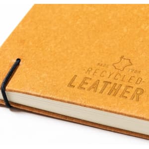 A notepad with a tan, recycled leather cover, featuring a black elastic band and a textured finish.