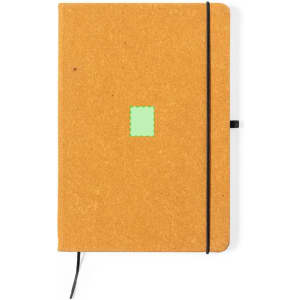 A brown notepad with a green square design, secured with a black elastic band, featuring a bookmark ribbon.