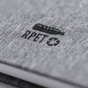 A grey notepad with a textured cover and a logo, featuring a sleek, modern design.