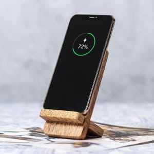 A wireless charger with a wooden stand displays a phone charging at 72%, set on a textured surface.