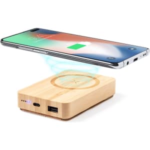 A wooden power bank with wireless charging capabilities, featuring a smartphone positioned above it.